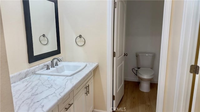 bathroom with vanity, wood finished floors, and toilet