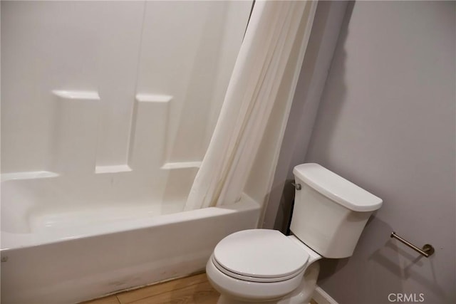 bathroom with baseboards, shower / tub combo with curtain, wood finished floors, and toilet