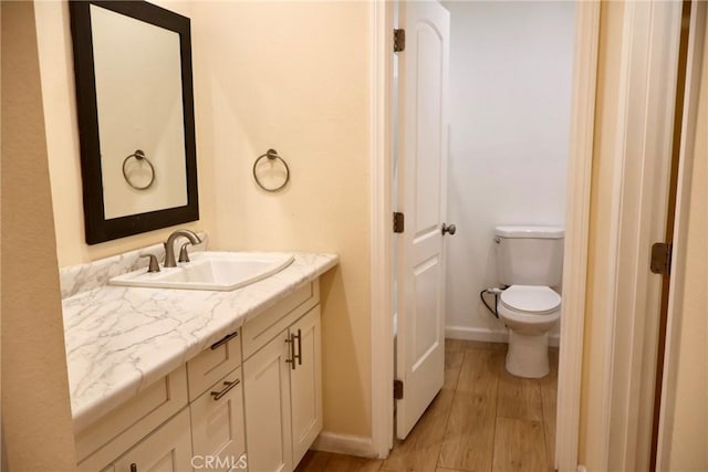 bathroom featuring vanity, baseboards, toilet, and wood finished floors