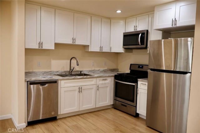 kitchen with light wood-style floors, a sink, white cabinets, and stainless steel appliances