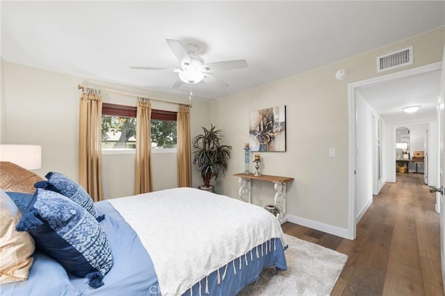 bedroom featuring wood finished floors, visible vents, arched walkways, baseboards, and ceiling fan