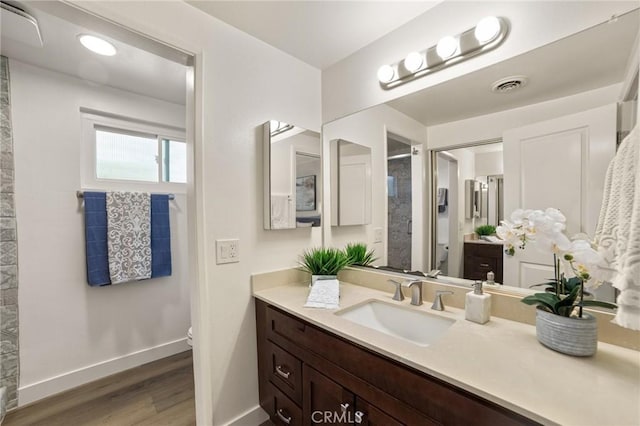 bathroom with toilet, baseboards, visible vents, walk in shower, and wood finished floors