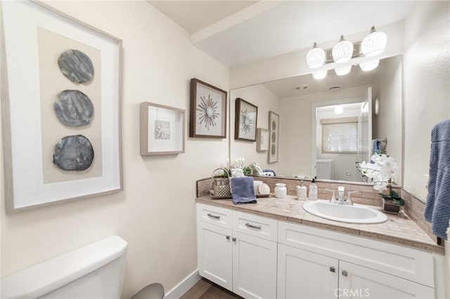 bathroom with baseboards, toilet, vanity, wood finished floors, and decorative backsplash