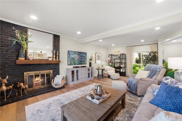 living room featuring beamed ceiling, a fireplace, ornamental molding, recessed lighting, and wood finished floors