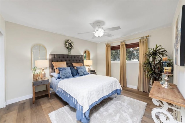 bedroom featuring light wood finished floors, baseboards, and a ceiling fan