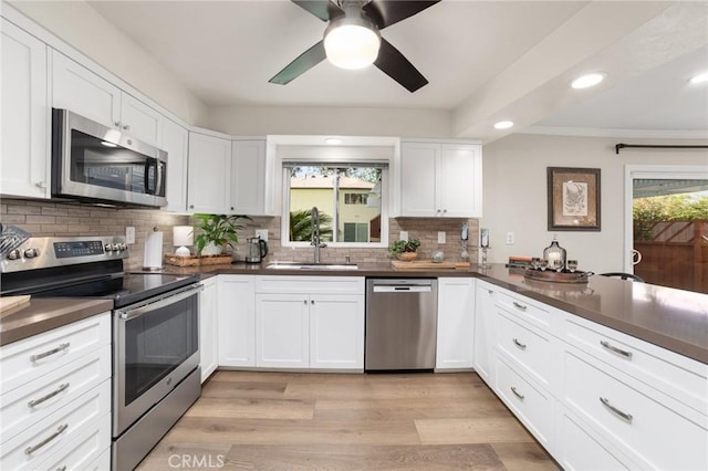 kitchen featuring backsplash, dark countertops, ceiling fan, stainless steel appliances, and a sink