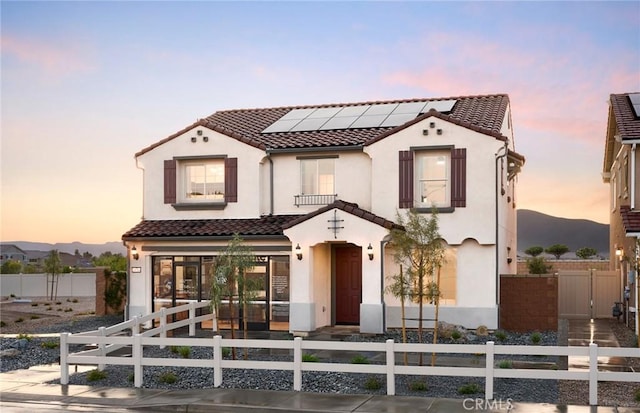 29754 Laurel Ct, Menifee, CA 92584 - mediterranean / spanish house featuring a fenced front yard, roof mounted solar panels, a tile roof, and stucco siding