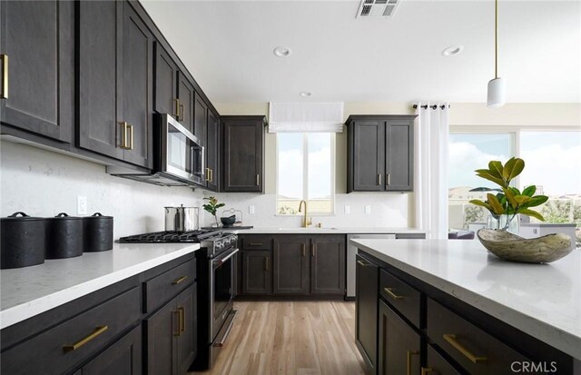 29754 Laurel Ct, Menifee, CA 92584 - kitchen featuring stainless steel appliances, light wood-type flooring, recessed lighting, decorative light fixtures, and light stone countertops