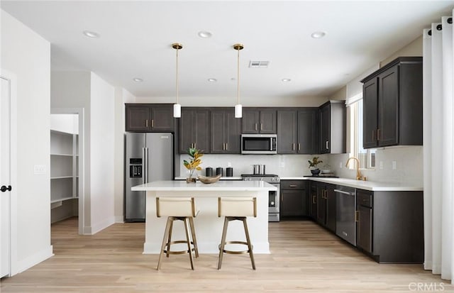 29754 Laurel Ct, Menifee, CA 92584 - kitchen featuring appliances with stainless steel finishes, light wood-style flooring, a kitchen breakfast bar, a kitchen island, and recessed lighting