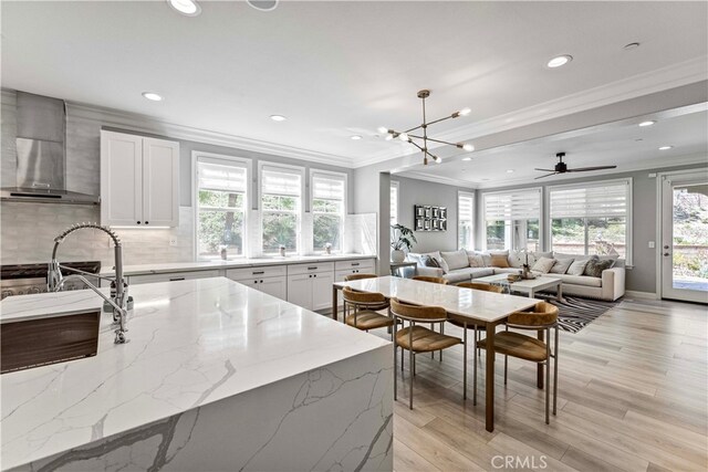 3905 Elderberry Cir, Corona, CA 92882 - kitchen featuring white cabinetry, tasteful backsplash, light wood-type flooring, light stone counters, and wall chimney exhaust hood