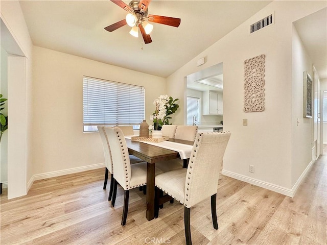 dining space featuring vaulted ceiling, baseboards, visible vents, light wood-style floors, and ceiling fan