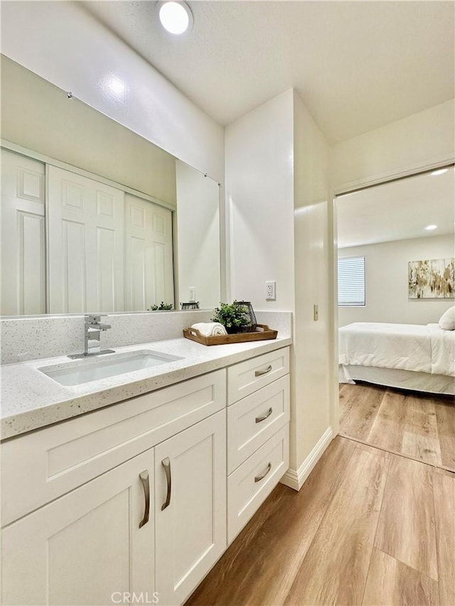 bathroom featuring vanity, baseboards, ensuite bathroom, and wood finished floors