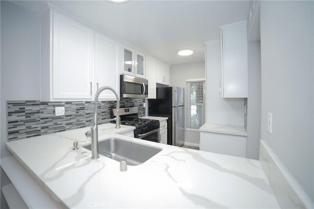 kitchen featuring stainless steel appliances, glass insert cabinets, backsplash, and white cabinets