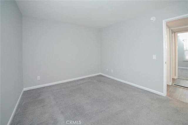 carpeted spare room featuring baseboards