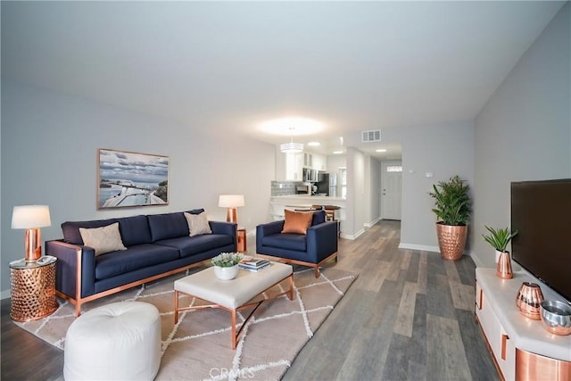 living room with visible vents, baseboards, and wood finished floors