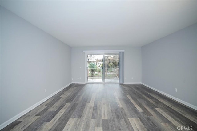 spare room featuring baseboards and dark wood-style flooring