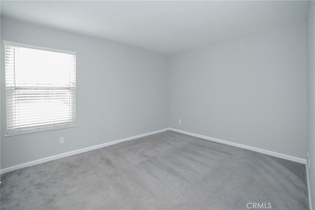 carpeted spare room featuring baseboards