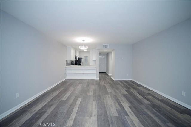 unfurnished living room featuring visible vents, dark wood-type flooring, and baseboards