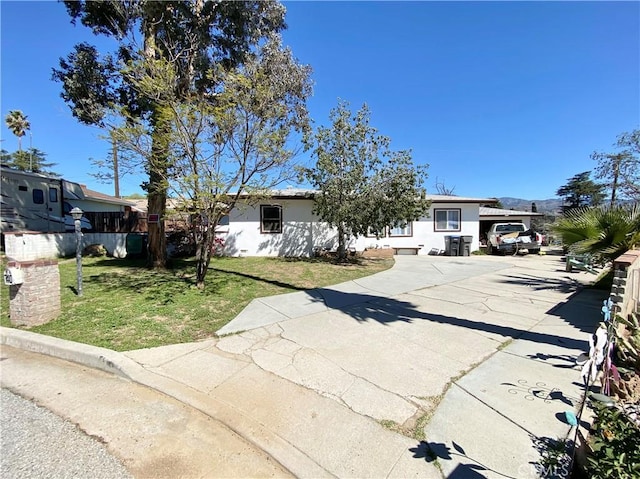 view of front of home featuring a front yard, driveway, stucco siding, and fence