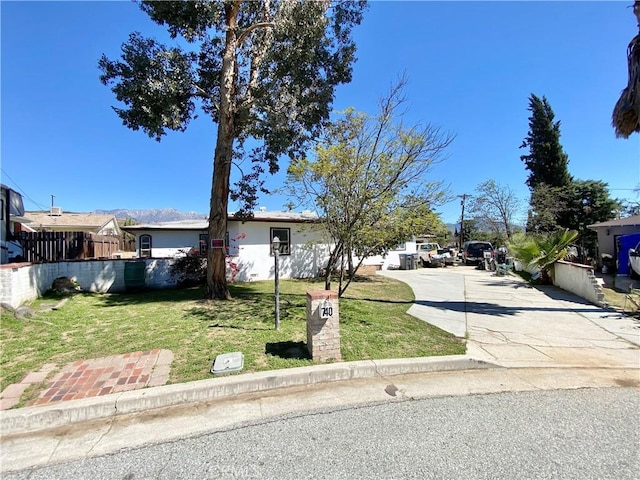 view of front of home with fence, concrete driveway, and a front yard