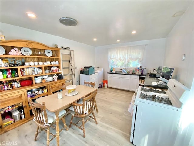kitchen with gas range gas stove, white cabinetry, light wood-type flooring, independent washer and dryer, and recessed lighting
