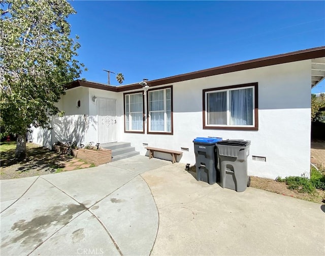 view of front of house featuring stucco siding and a patio