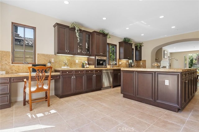 kitchen featuring arched walkways, dark brown cabinets, recessed lighting, dishwasher, and backsplash