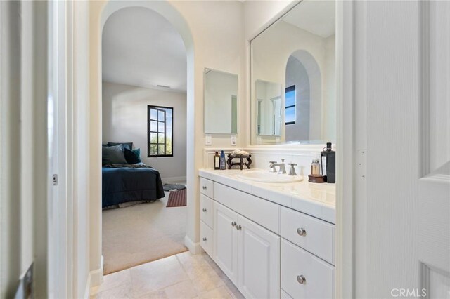 bathroom featuring tile patterned flooring, vanity, baseboards, and connected bathroom