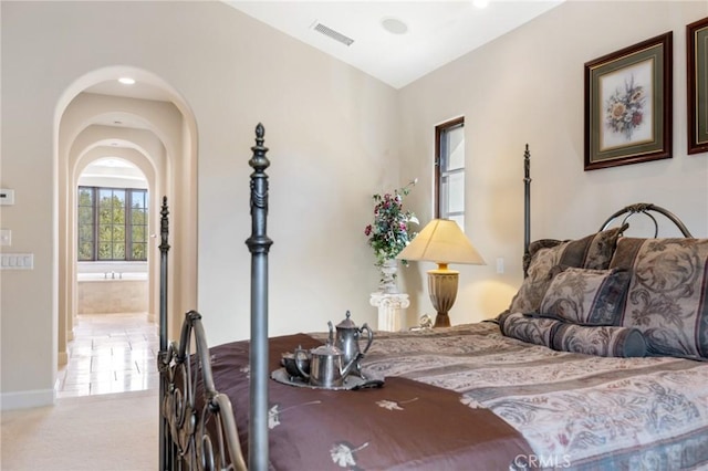 bedroom with arched walkways, baseboards, and visible vents