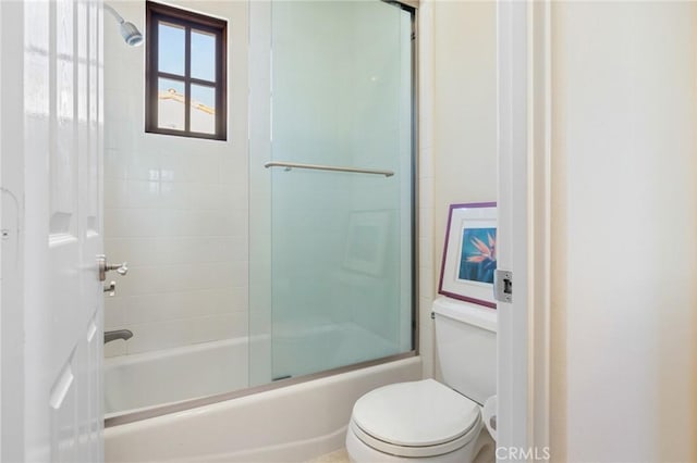 bathroom with combined bath / shower with glass door and toilet