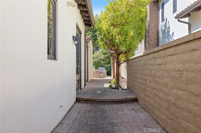 view of side of property with a patio, stucco siding, and fence