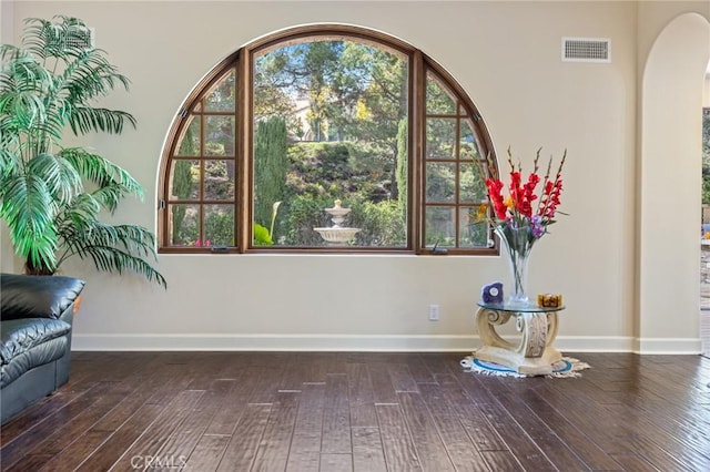 details featuring arched walkways, wood finished floors, baseboards, and visible vents