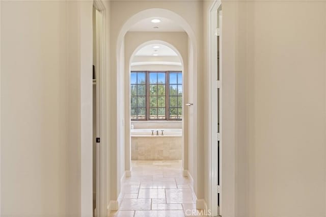 corridor with stone tile flooring and baseboards