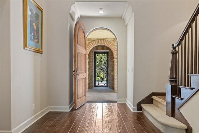 entrance foyer with stairs, dark wood-style flooring, and baseboards