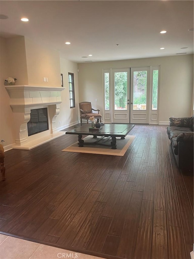 living area with a glass covered fireplace, recessed lighting, wood-type flooring, and baseboards