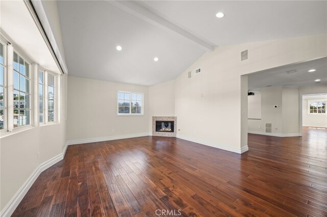 unfurnished living room with beamed ceiling, baseboards, wood-type flooring, and a glass covered fireplace
