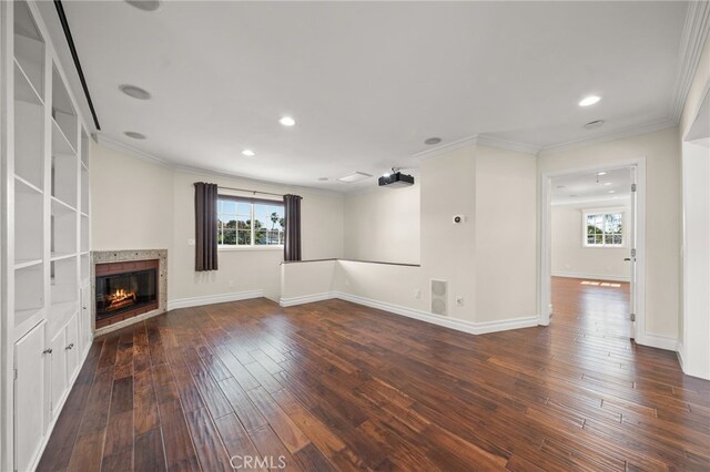 unfurnished living room featuring crown molding, a glass covered fireplace, recessed lighting, wood-type flooring, and baseboards