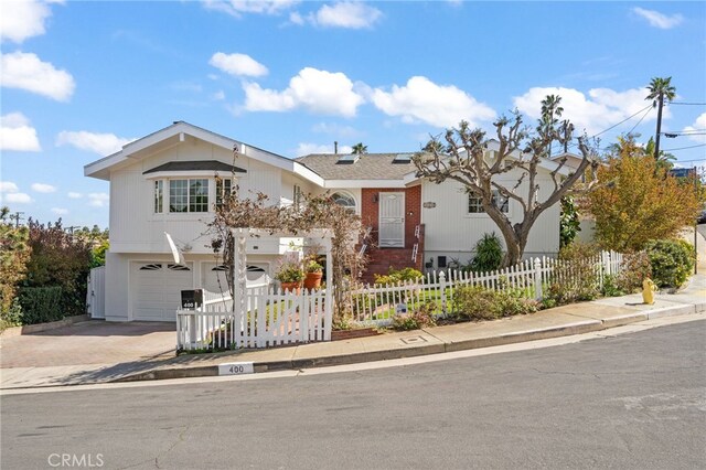 view of front facade featuring a fenced front yard, a garage, and driveway