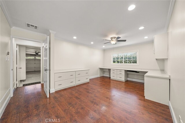 unfurnished office with built in desk, ornamental molding, a ceiling fan, dark wood finished floors, and recessed lighting