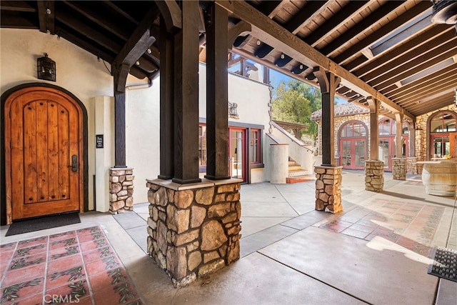 entrance to property with french doors, stone siding, and stucco siding