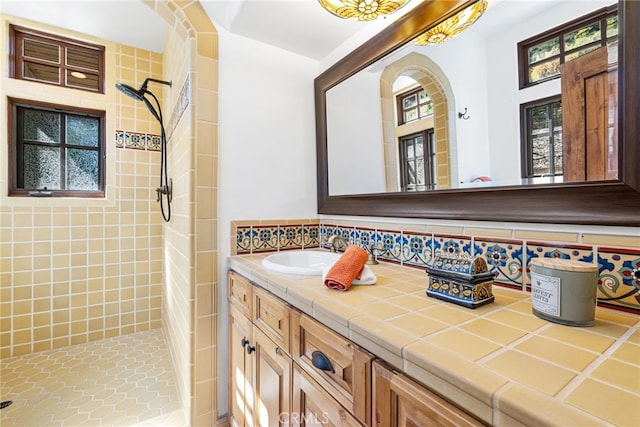 full bathroom featuring a tile shower, vanity, and plenty of natural light