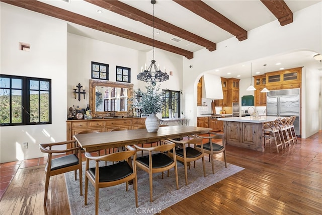 dining area with arched walkways, a towering ceiling, and dark wood finished floors