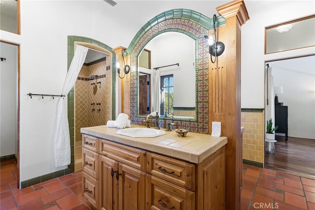 bathroom featuring vanity, tiled shower, and tile walls