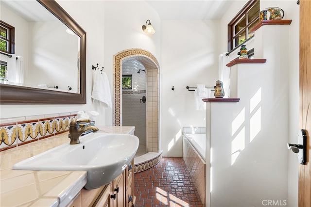 bathroom with a relaxing tiled tub, brick floor, tiled shower, and vanity