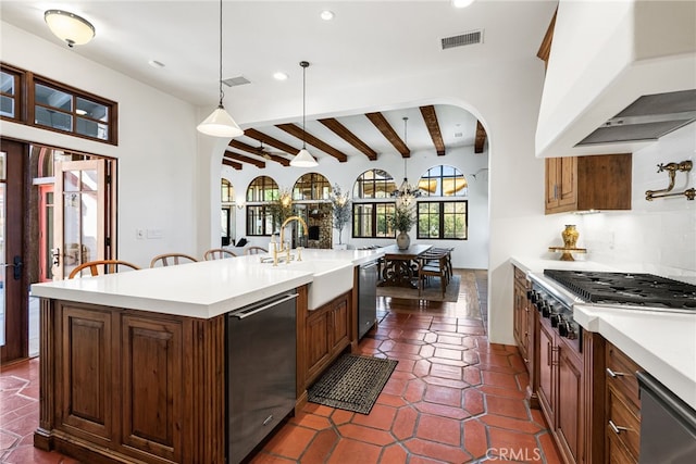 kitchen featuring light countertops, stainless steel appliances, range hood, a sink, and visible vents