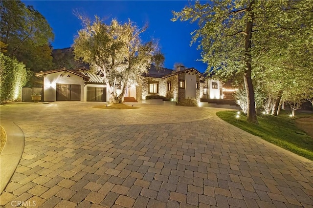 mediterranean / spanish home with stucco siding, a garage, and curved driveway