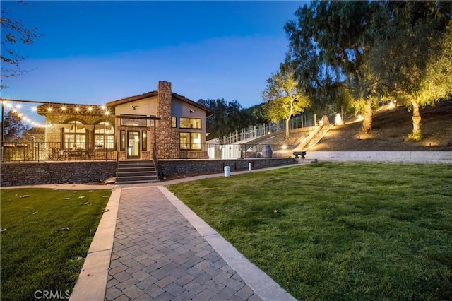 back of property with fence, stucco siding, and a yard