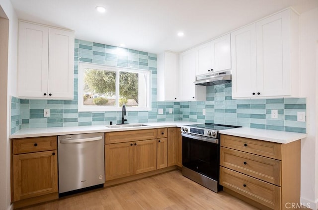 kitchen featuring a sink, light countertops, appliances with stainless steel finishes, and under cabinet range hood