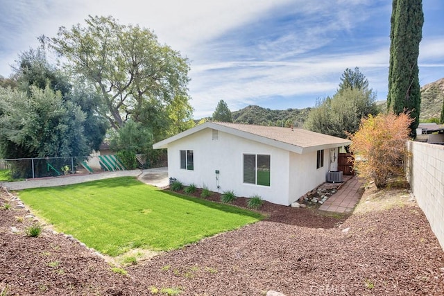 back of property with central AC, a yard, a fenced backyard, a patio, and stucco siding