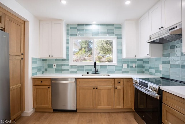 kitchen featuring under cabinet range hood, light countertops, a sink, stainless steel appliances, and decorative backsplash